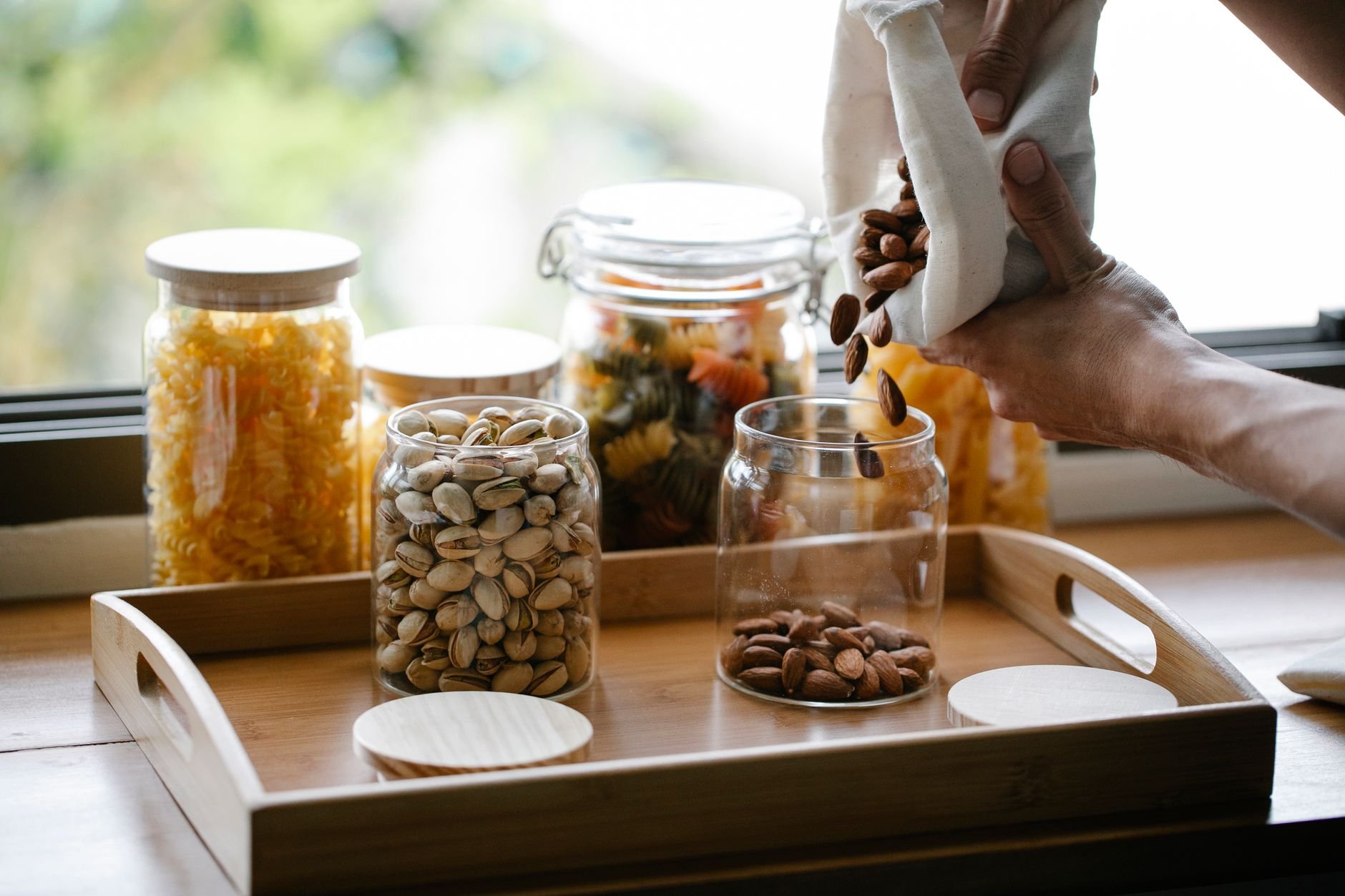 Productos sostenibles de cocina: bolsas reutilizables y tarros de vidrio en una bandeja de madera
